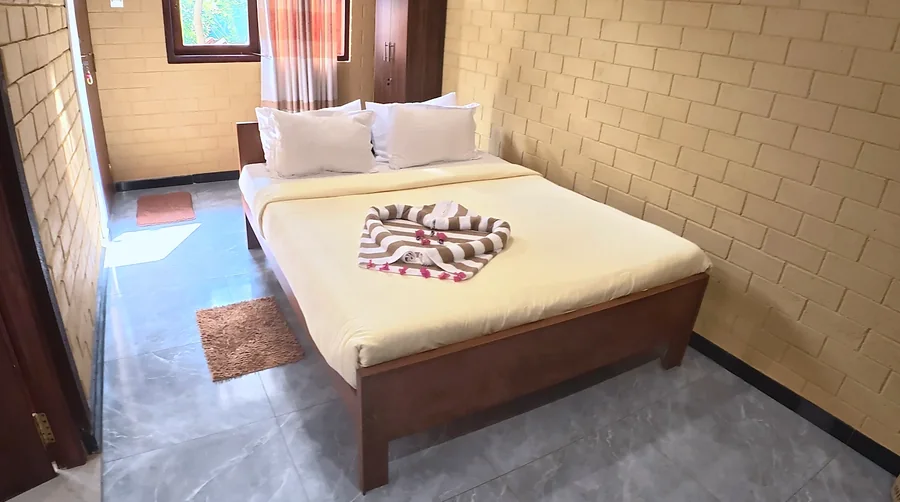 غرفة نوم بجدران من الطوب الأصفر وسرير خشبي — Syndeo Garden, هيكادوا